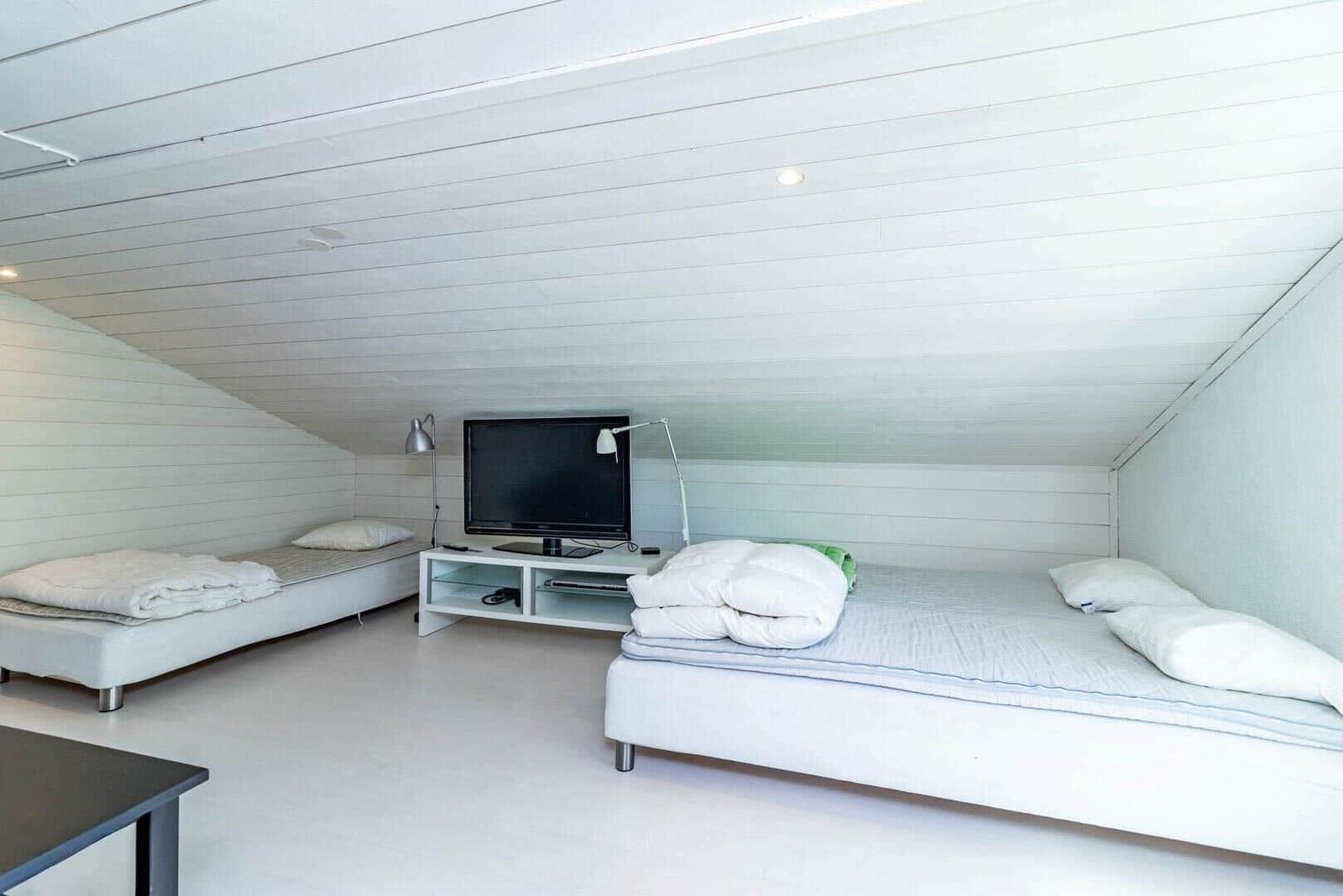 Zimmer mit zwei Betten, Fernseher und Lampe an der Wand.