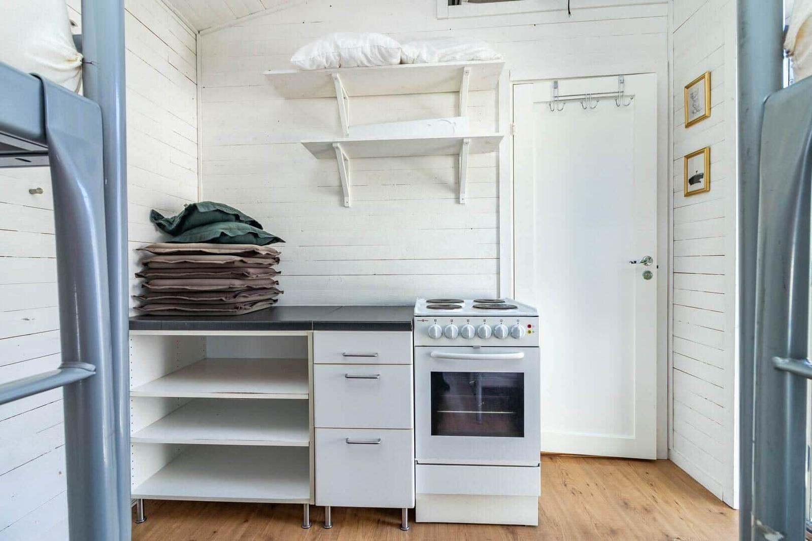 Küche mit Kochfeld, Schrank und Regal. Tür und Wand mit Bildern.