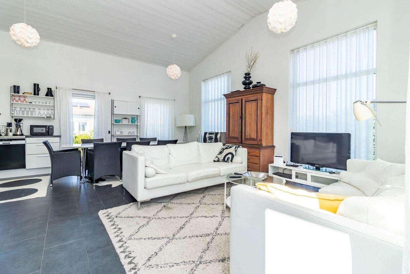 Wohn- und Essbereich mit Sofa, Fernseher und Küchenzeile.