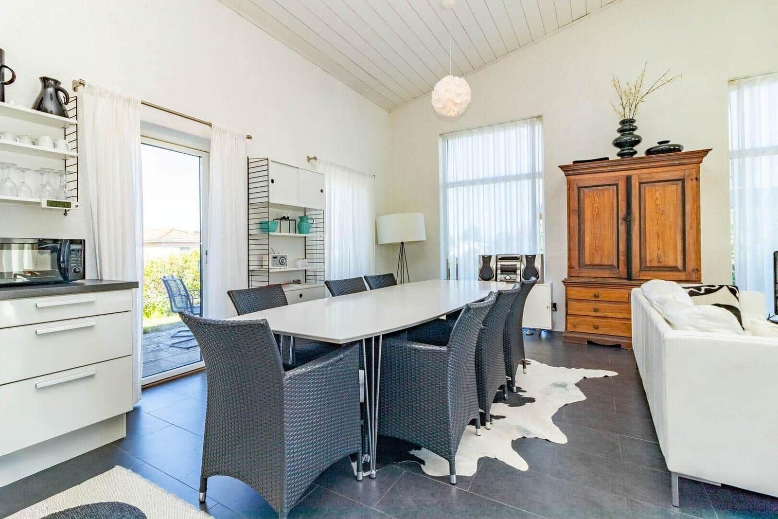 Essbereich mit Esstisch, Stühlen und Wohnbereich mit Sofa und Holzschrank.