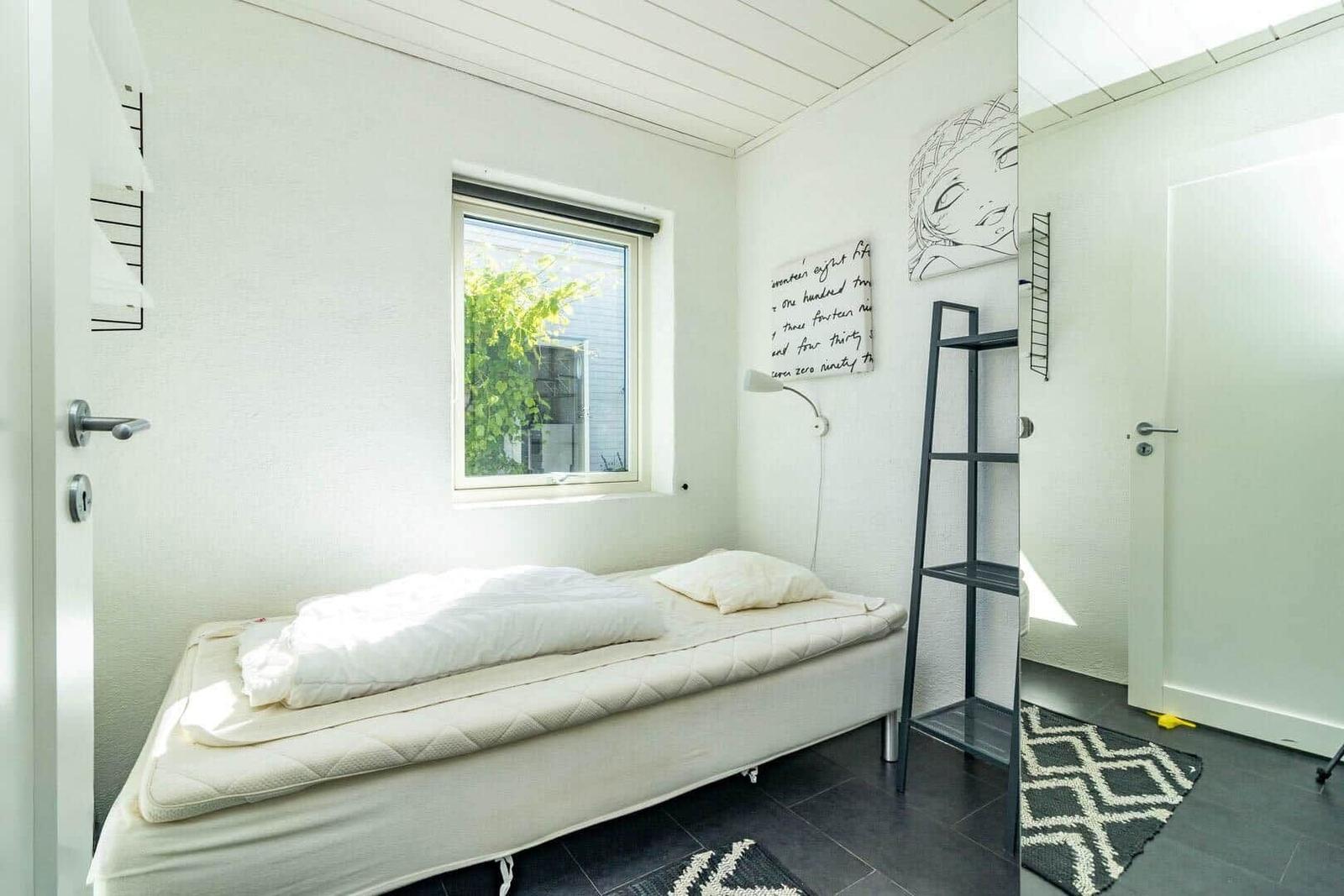 Schlafzimmer mit Bett, Fenster und Wanddekoration.