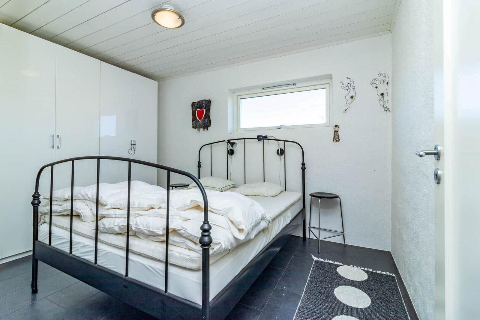 Schlafzimmer mit Bett, Kleiderschrank und Fenster.