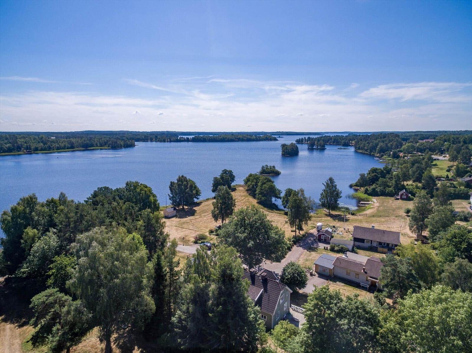Haus am See mit Wald und Inseln im Hintergrund.
