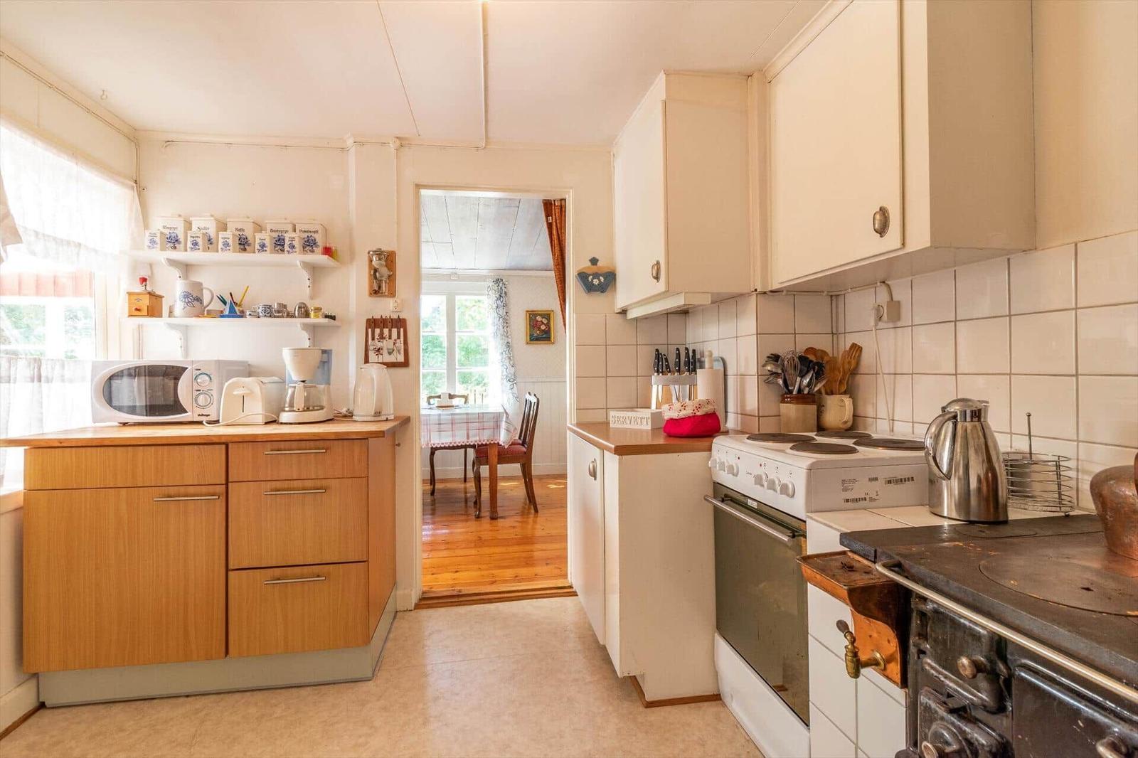 Küche mit Holzschränken, Kochfeld und Blick in das Esszimmer.