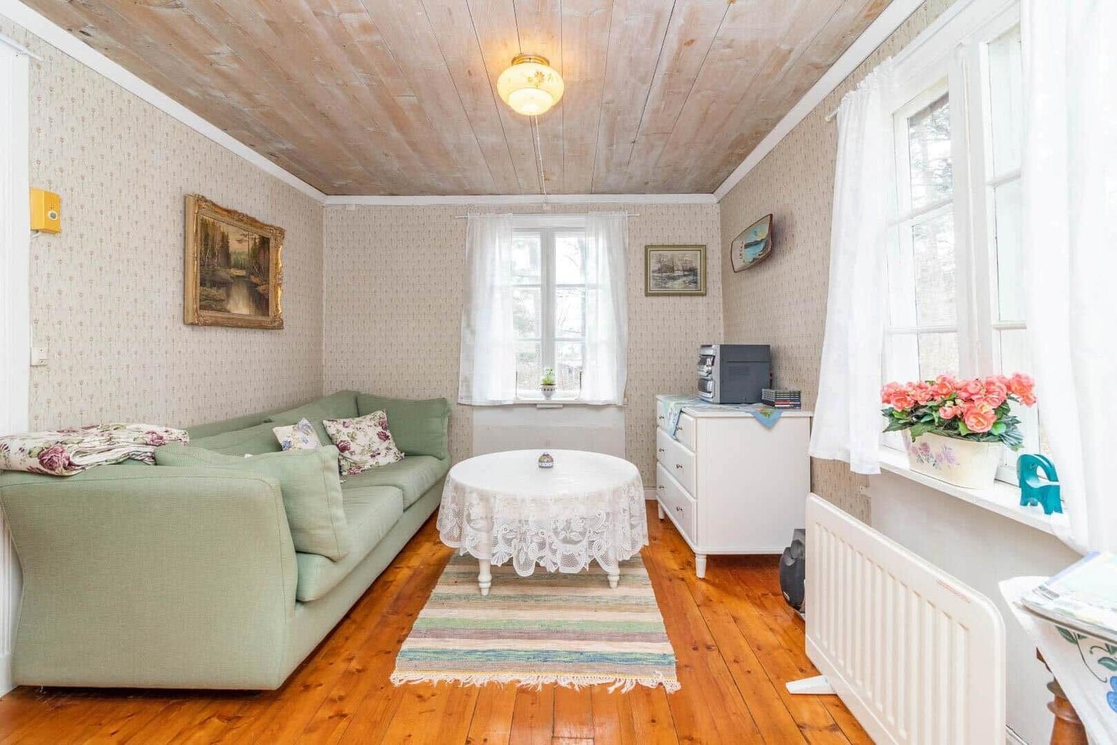 Ein Wohnzimmer mit grünem Sofa, runden Tisch und Holzboden.