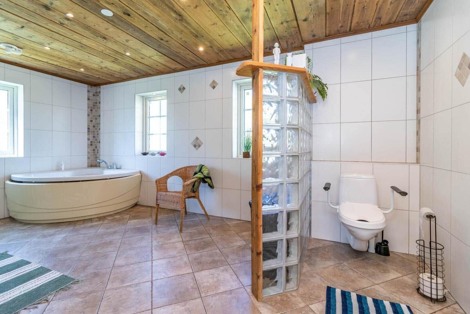 Badezimmer mit Badewanne, Toilette und Glasblockwand