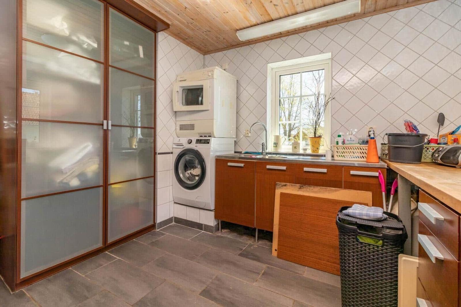 Wohnung mit Waschmaschine, Spüle und Fenster. Holzdecke und Schrank mit Glasfront.
