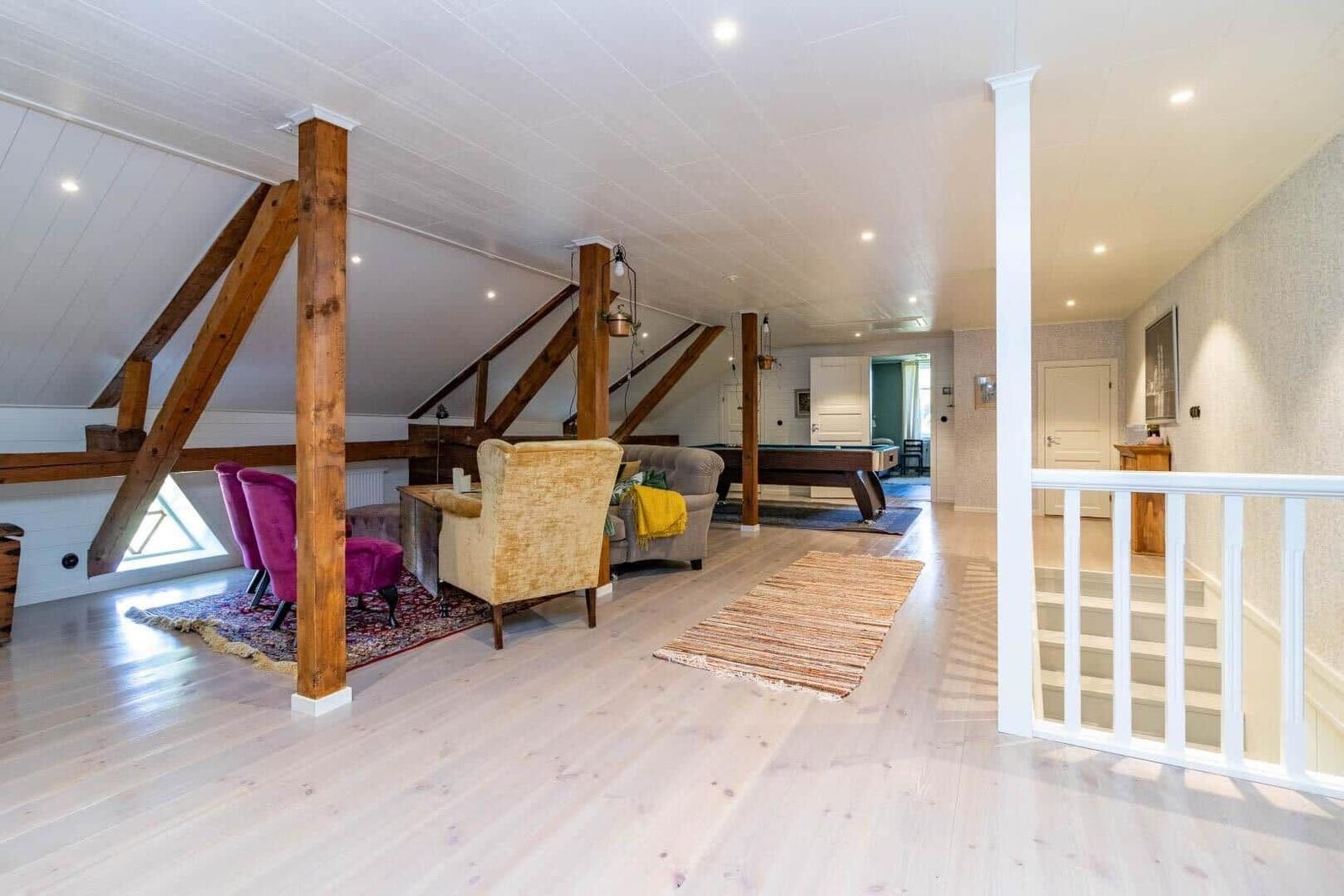 Großer Wohnraum mit Holzbalken, Pooltable und Sitzgelegenheiten.
