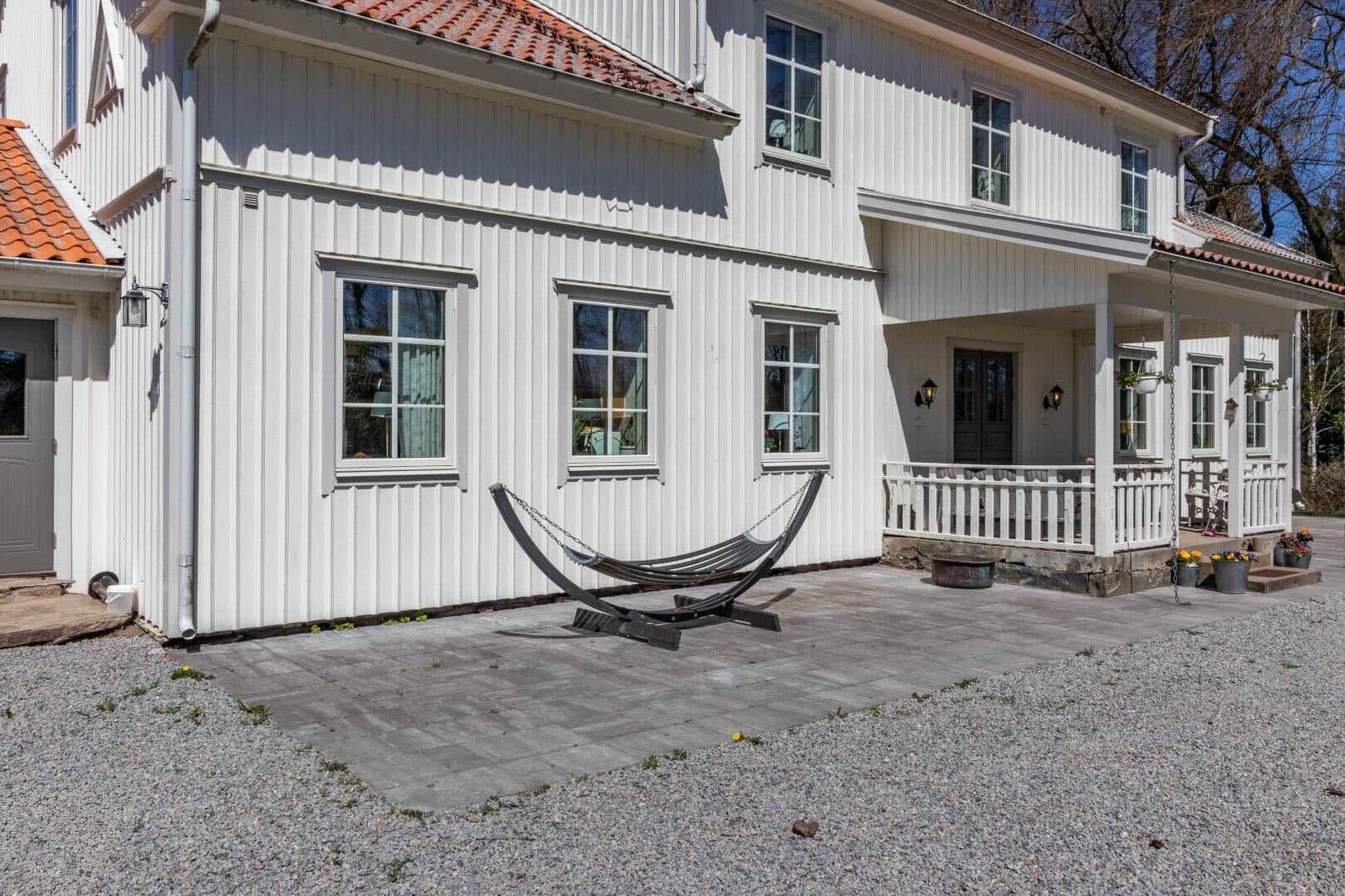 Haus mit weißer Fassade, Terrasse und Hängemöbel im Vorgarten.