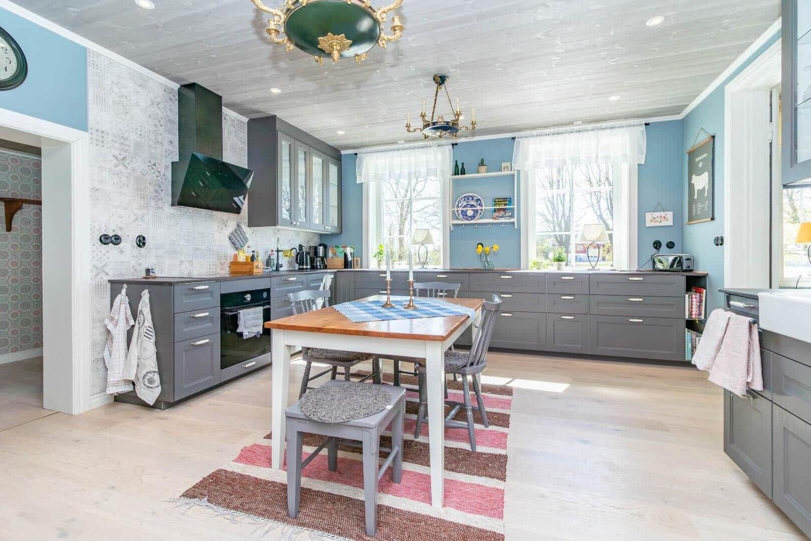 Küche mit grauen Schränken, Holzfußboden und Essbereich mit Tisch.