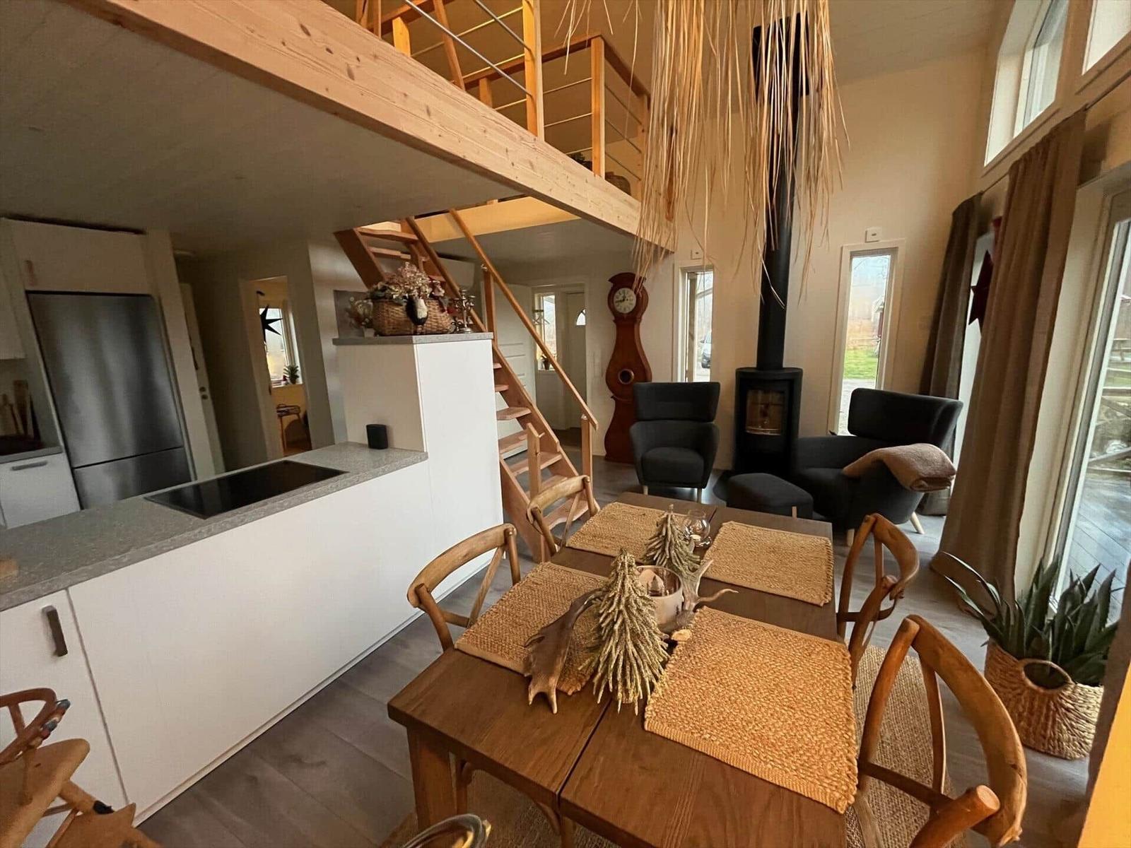 Esszimmer mit Holztisch, Küchenbereich und Aufgang zur Galerie