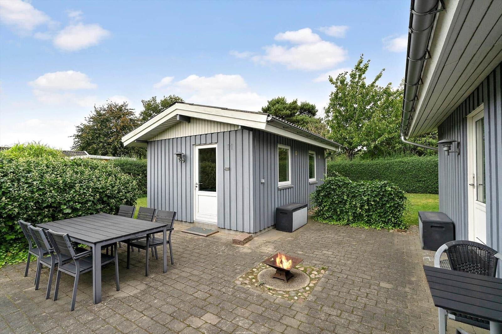 Hinterhof mit Grillplatz, Tisch und Stühlen. Kleines Haus mit Fenstern und Tür.