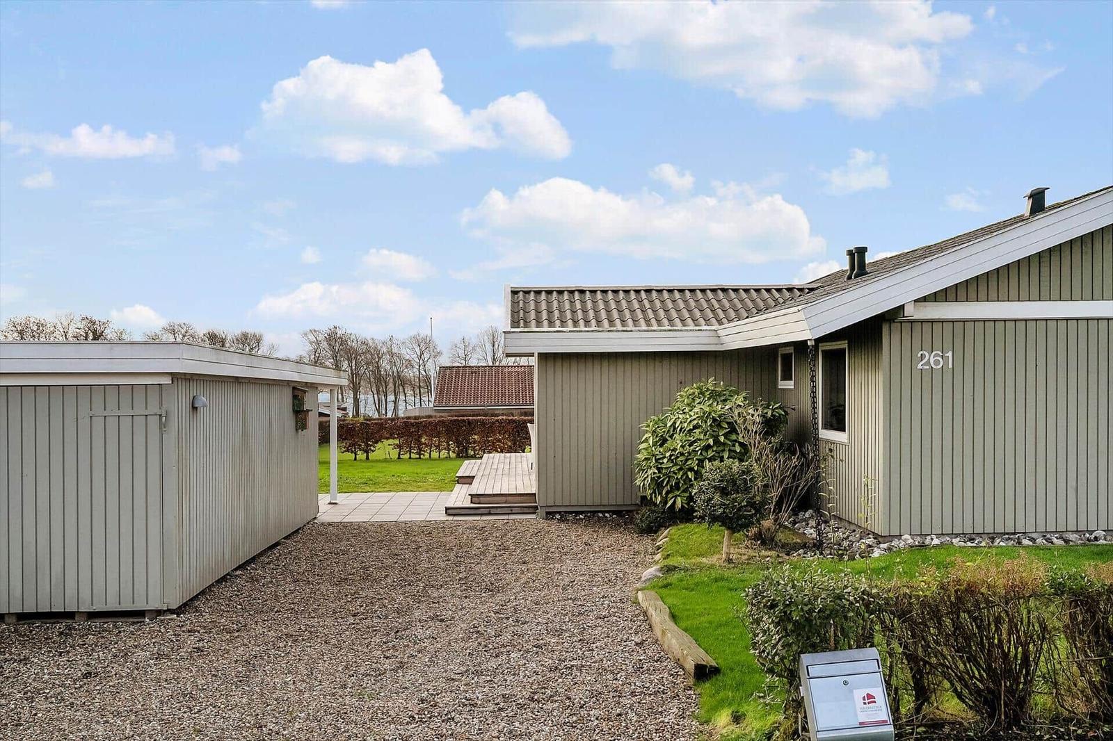 Haus mit Holzfassade, Garten und Terrasse unter blauem Himmel.