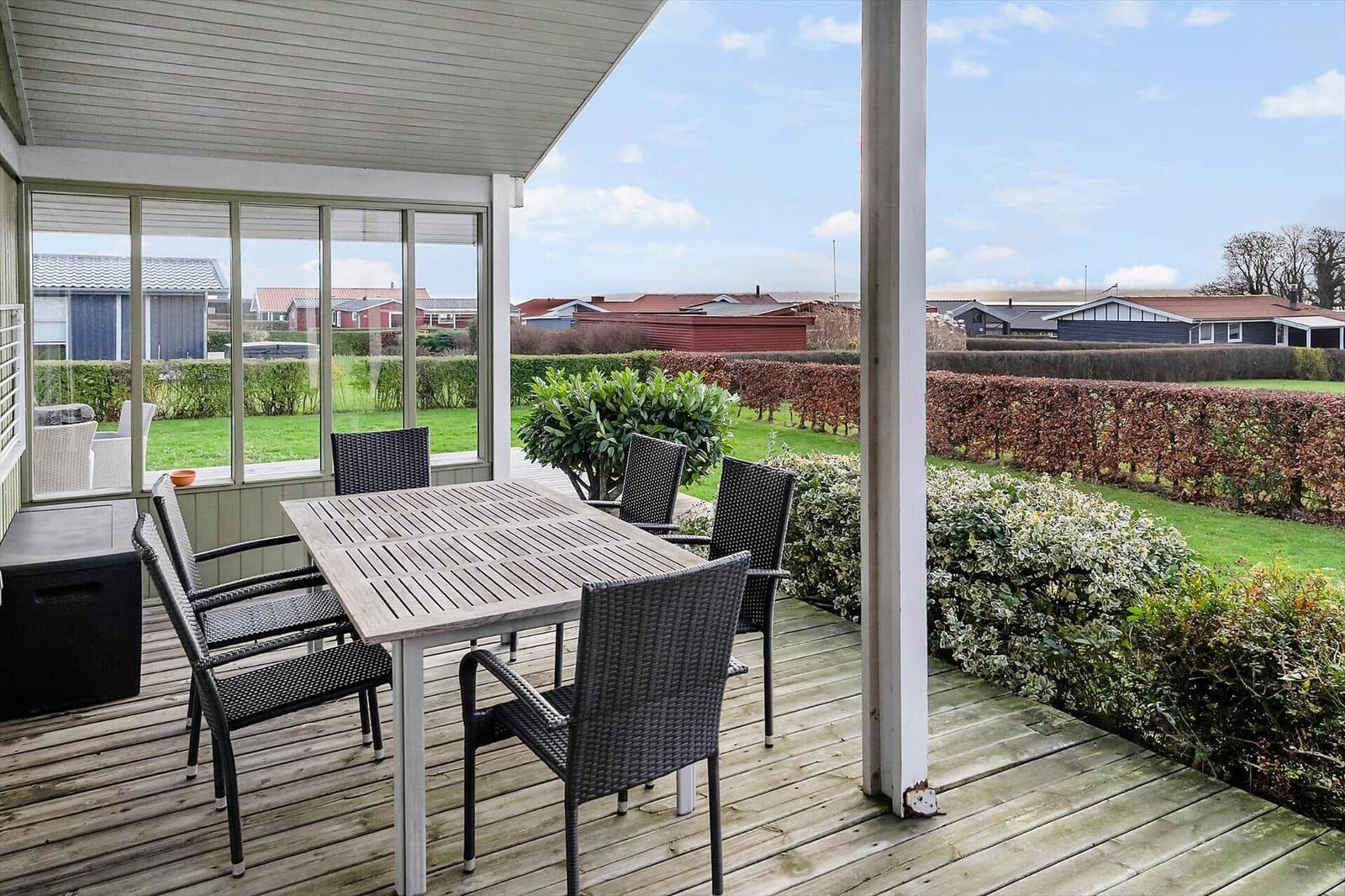 Terrasse mit Tisch und Stühlen, Blick auf Grünflächen und Häuser.