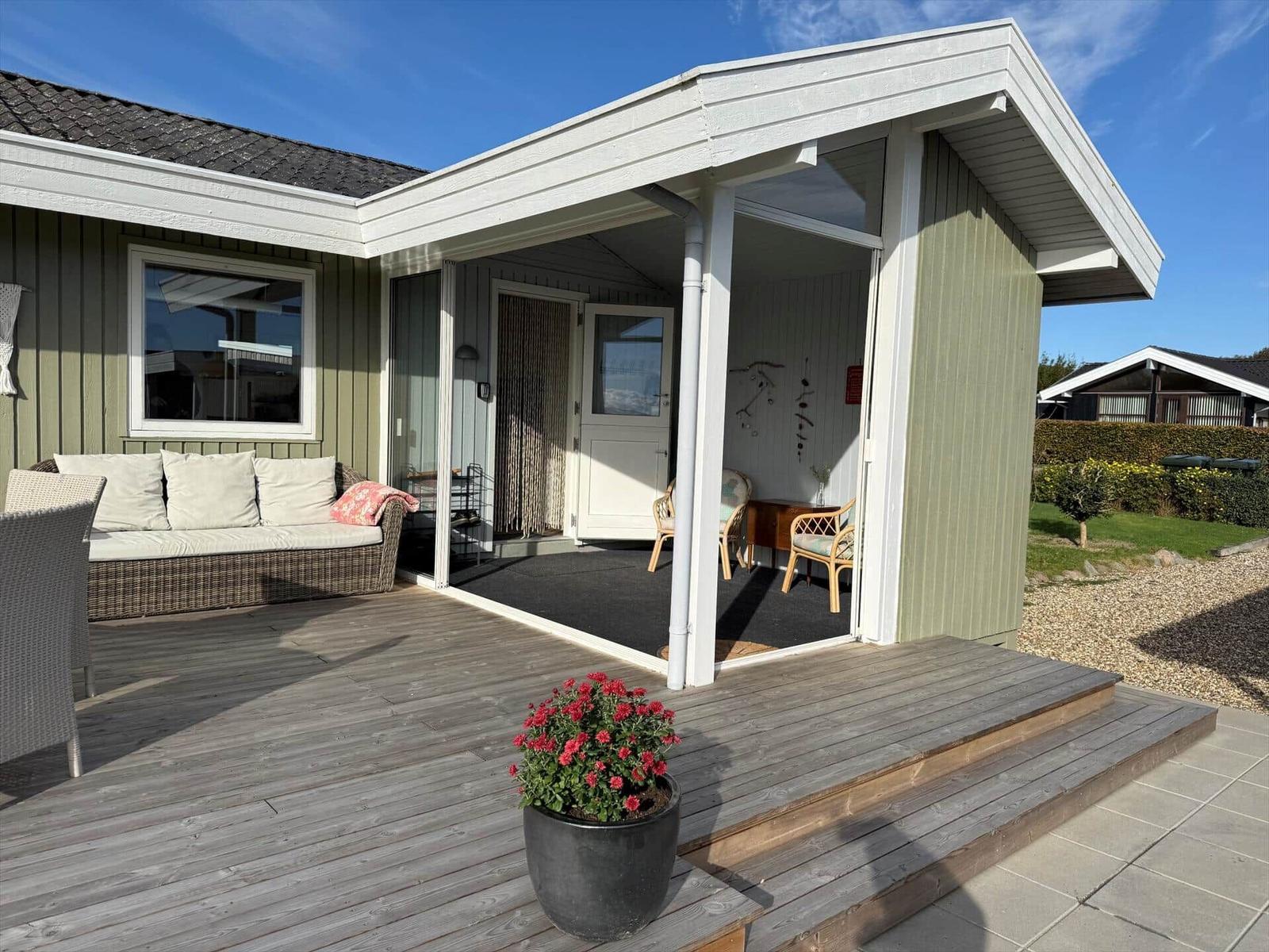 Terrasse mit Sitzgelegenheit und Blick ins Haus. Pflanze und Holzdielen.