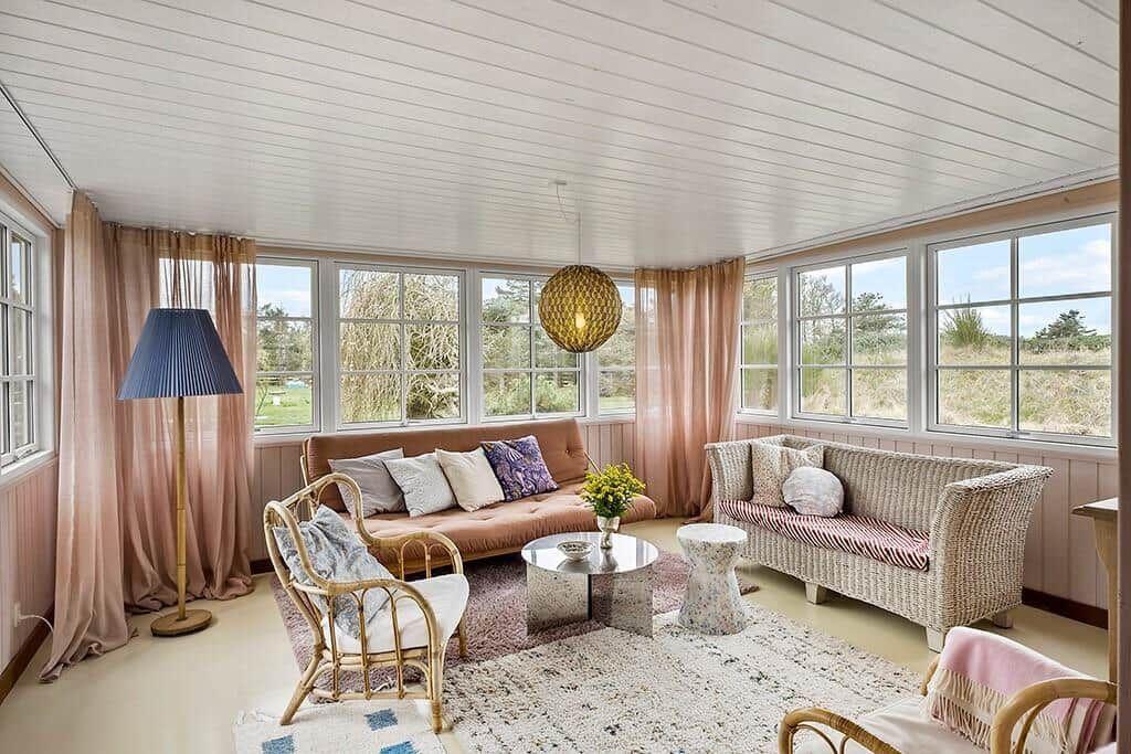 Living room with sofa, chairs, and large windows. View of green areas.