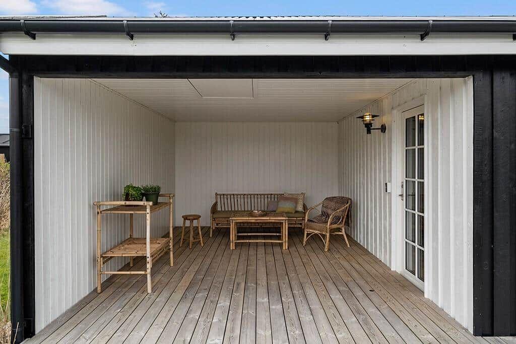 Patio with seating, table, and plants under roof.