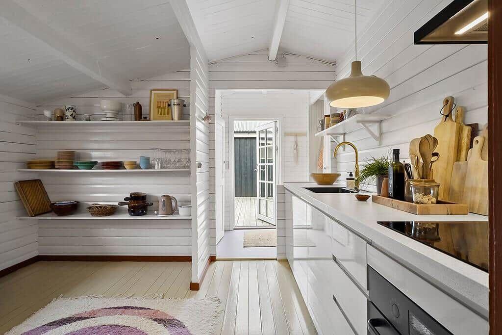 Kitchen with white cabinets, countertop, and shelves. Passage to terrace with doors.
