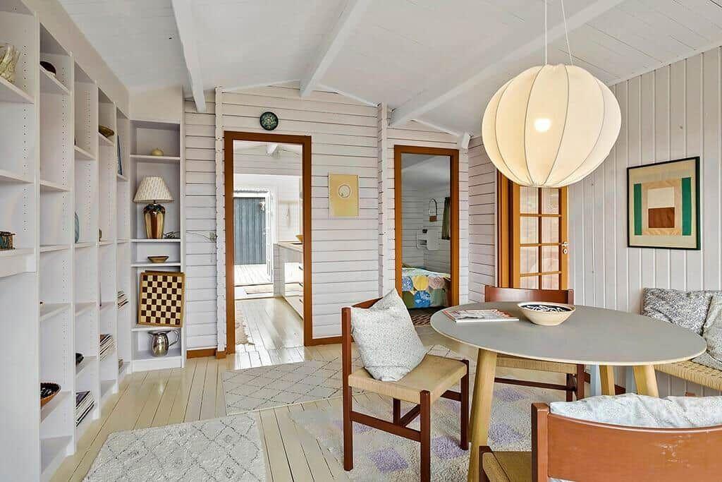 Dining area with round table, chairs, and large lamp. Picture on wall. Bookshelves on the left.