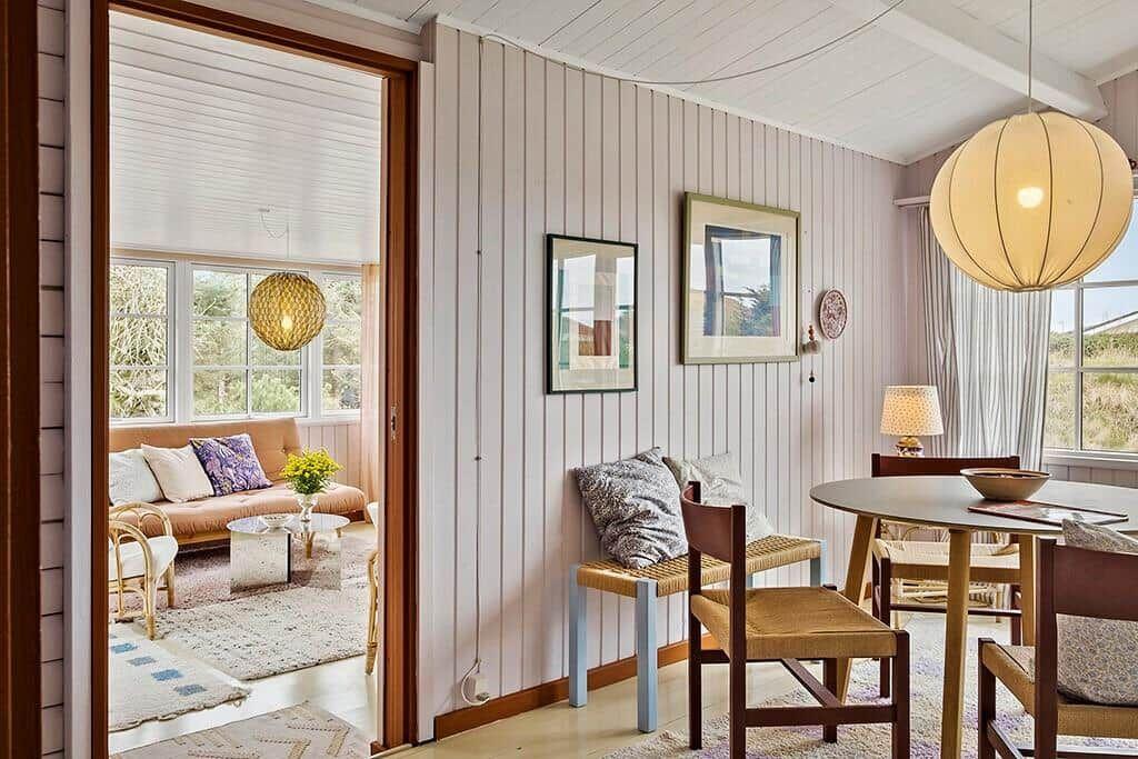 Dining room with round table and chairs. Passage to living room with sofa and window.