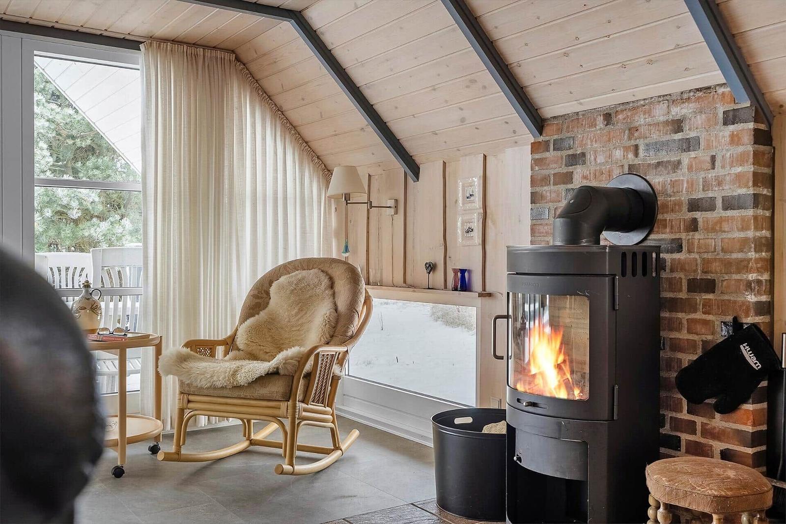 Raum mit Kamin, Schaukelstuhl und Fenster zum Außenbereich.