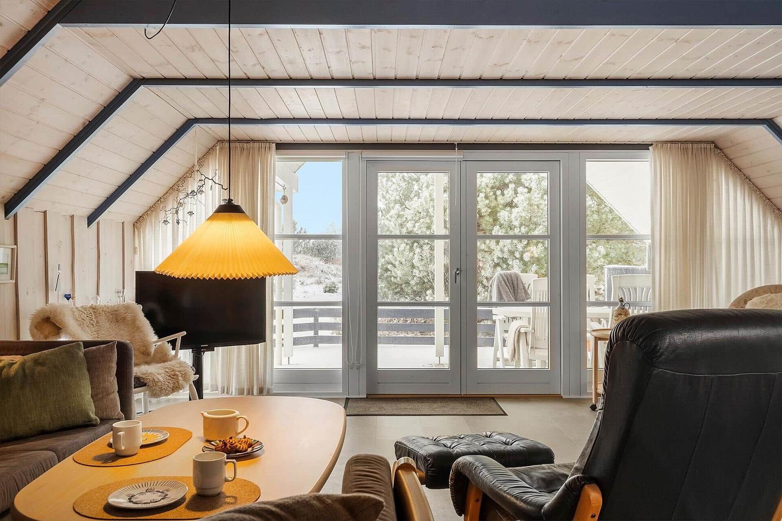 Wohnzimmer mit Essbereich, großen Fenstern und Blick auf die Terrasse.
