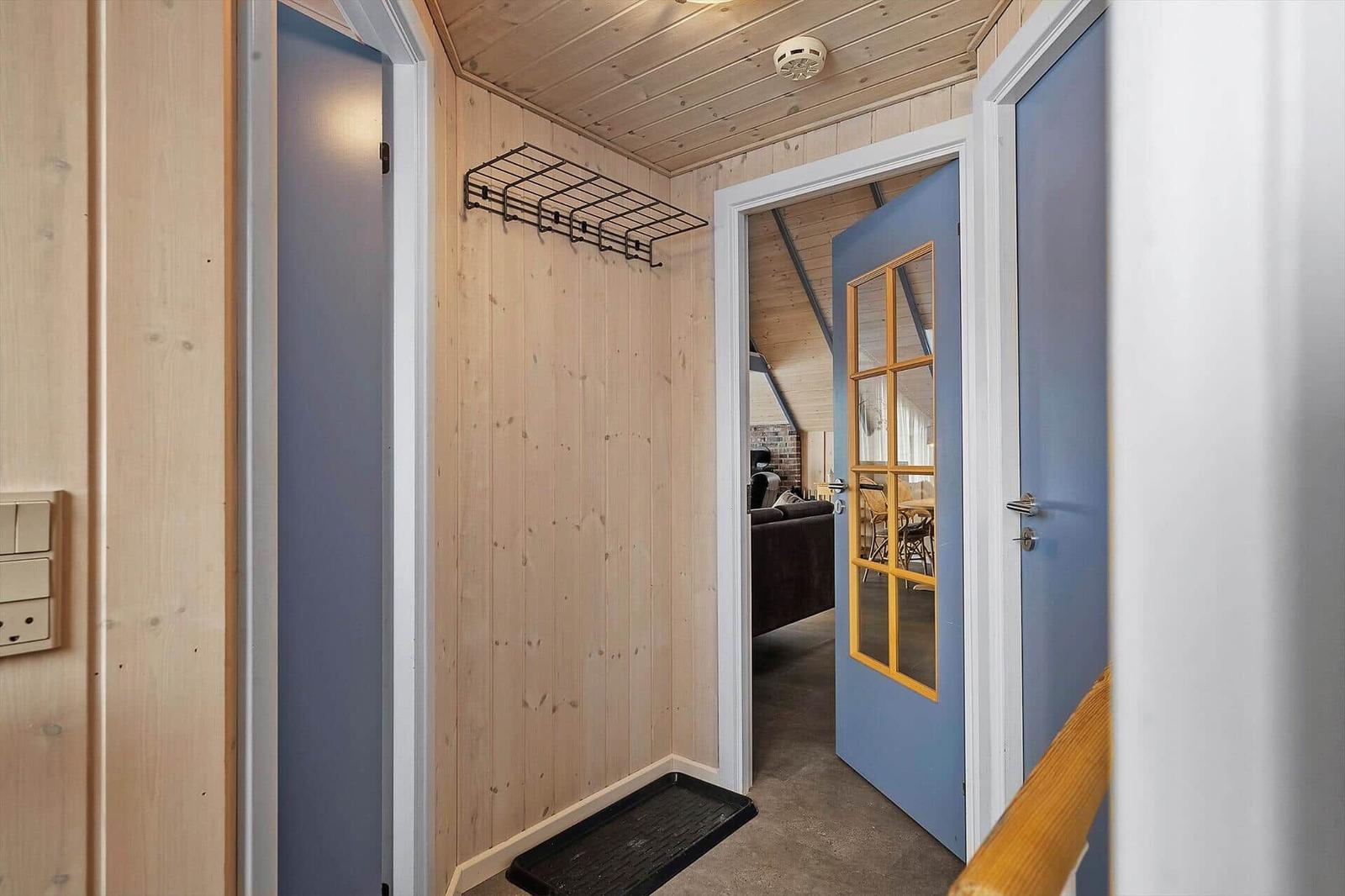 Höhenkorridor mit Holzwänden, blauer Tür und schwarzer Matte.