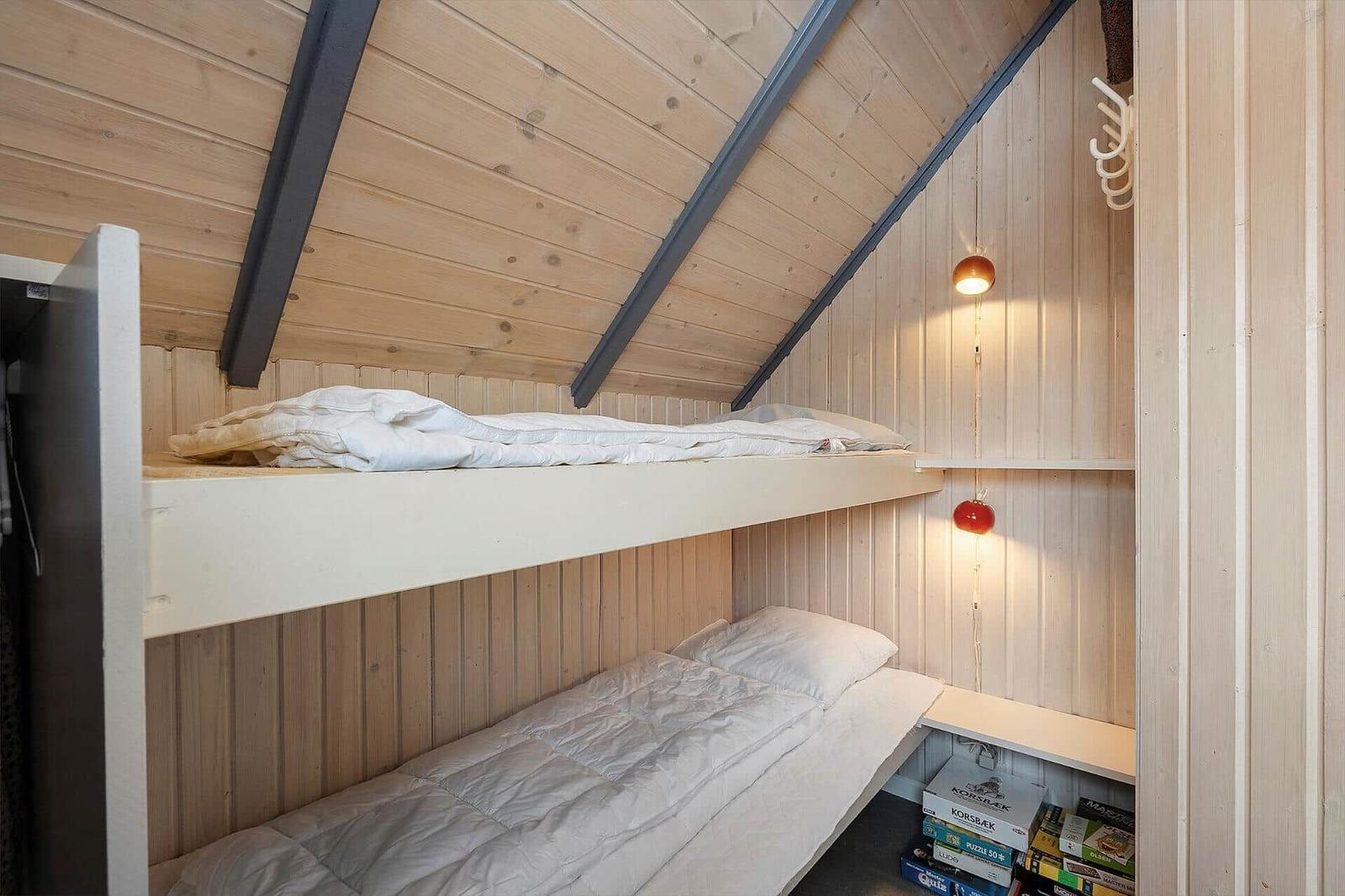 Doppelstockbett in einem Holzraum mit Dachschrägen und Wandlampen.