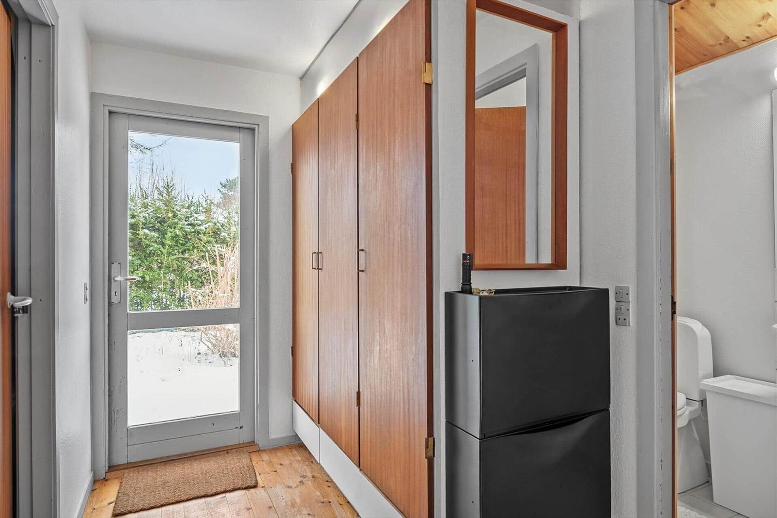Entrance with wooden floor, cabinet, mirror, and door to outside area.