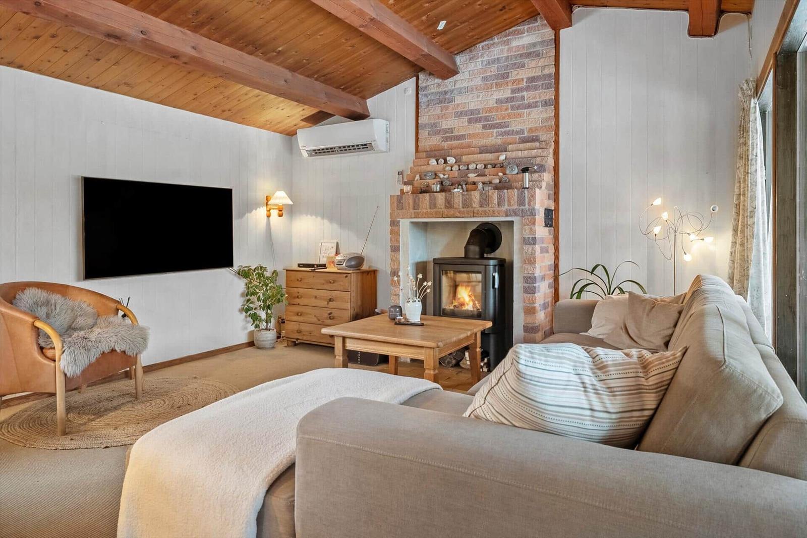Living room with fireplace, sofa, TV, and wooden ceiling.