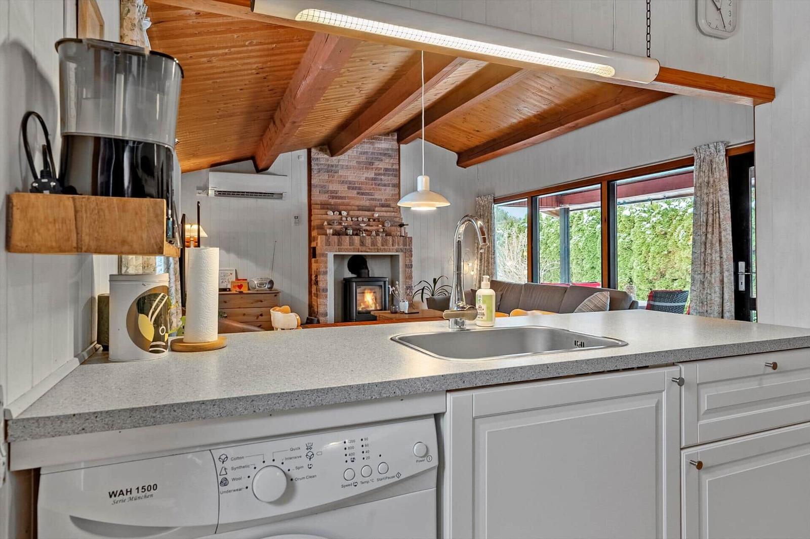 Kitchen with sink, dishwasher, and view into living area with fireplace.