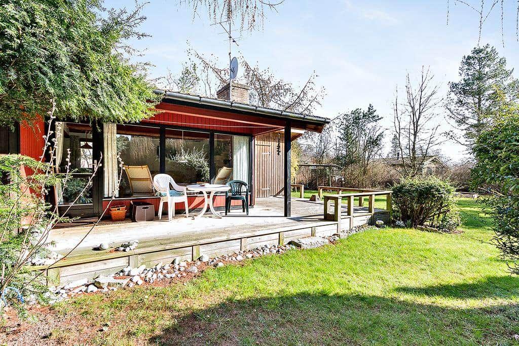 House with terrace, garden and seating. View of surrounding trees.