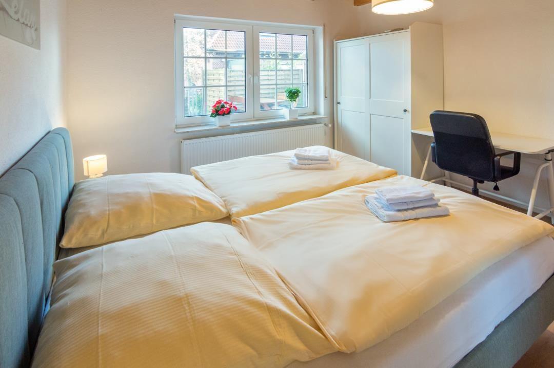 Double bed with linens, desk, wardrobe, and window with view.