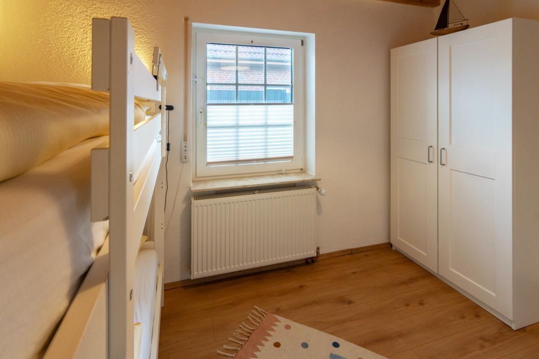 Room with bunk bed, window, and wardrobe