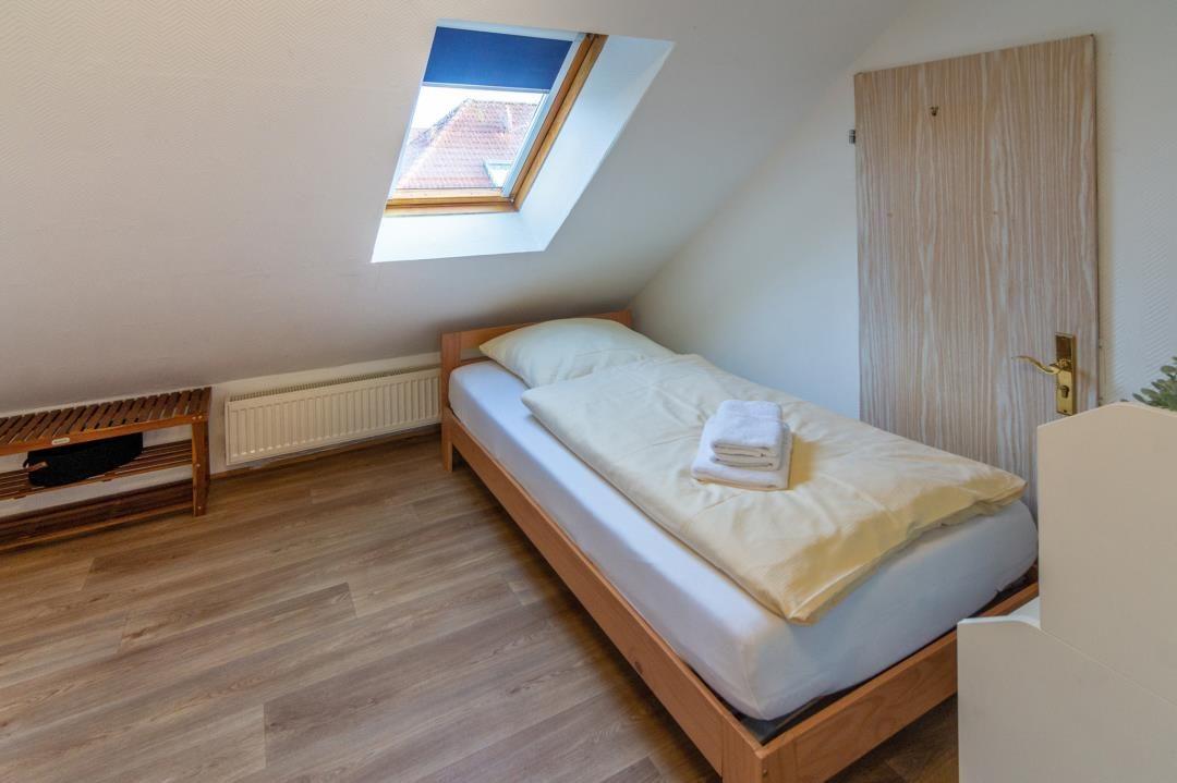 A bedroom with skylight, wooden bed, and wooden floor.
