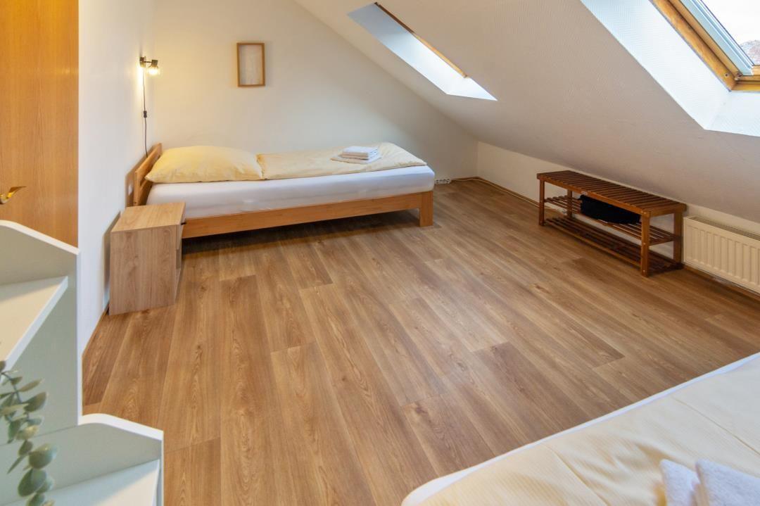 Bedroom with sloped ceiling, hardwood floor, and skylights.