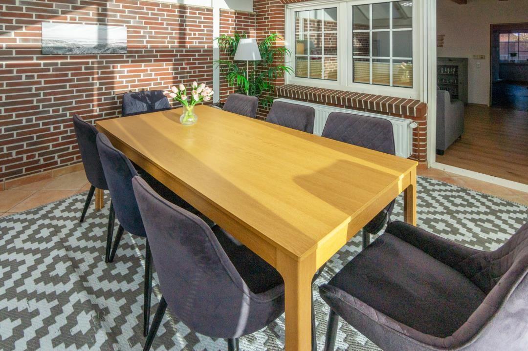 Dining room with wooden table, six chairs, and brick wall.