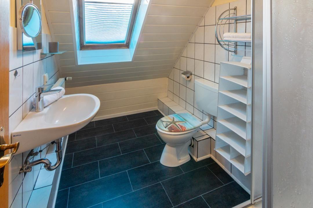 Bathroom with toilet, sink and shower under sloped ceilings