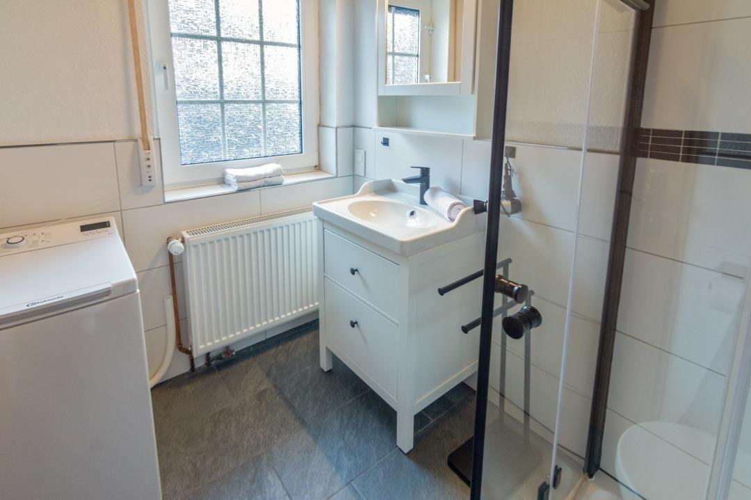 Bathroom with washing machine, sink, and shower.