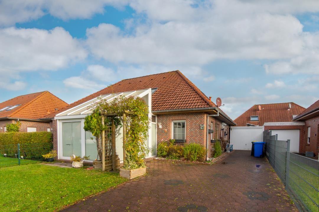 House with garden, terrace, and garage under blue sky.