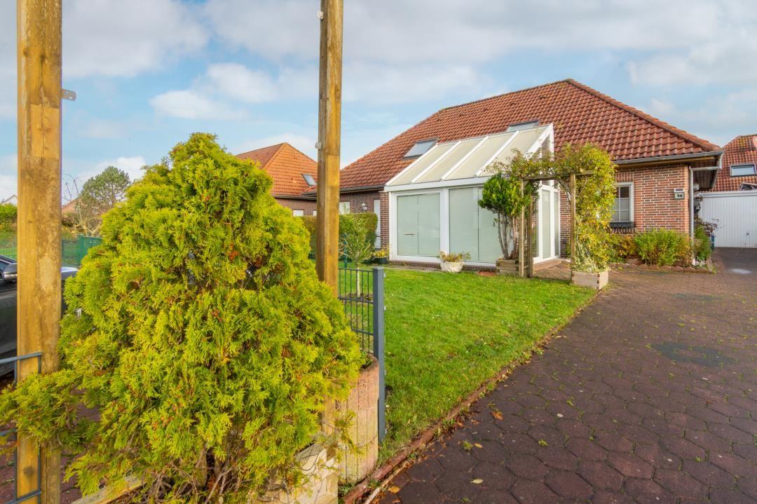 House with terrace and garden. Red roof and paved path.
