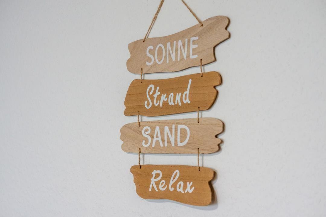 Wooden sign with words Sun, Beach, Sand and Relax on the wall.