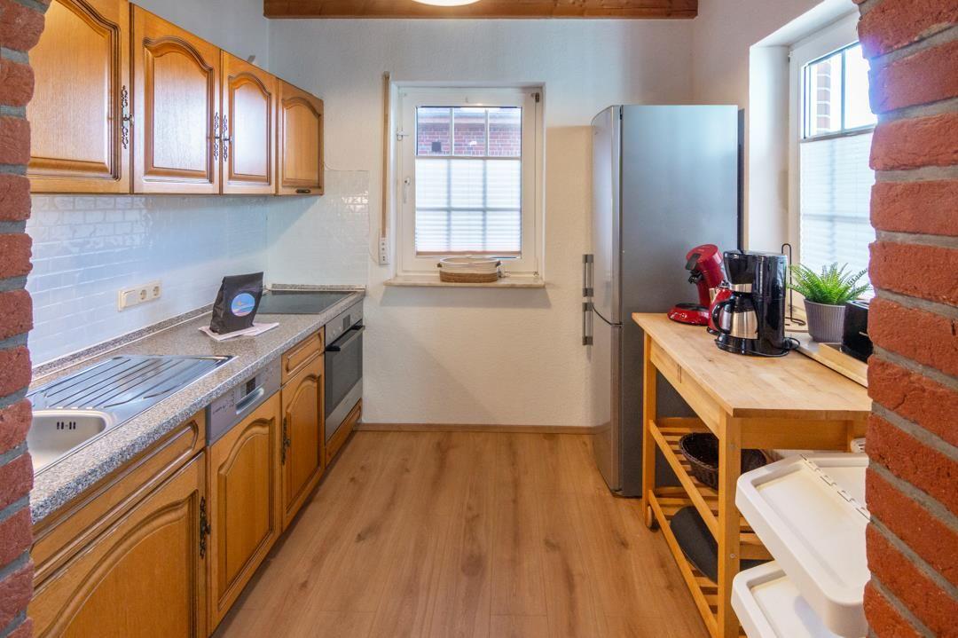 Kitchen with wooden cabinets, sink, refrigerator, and work surface.