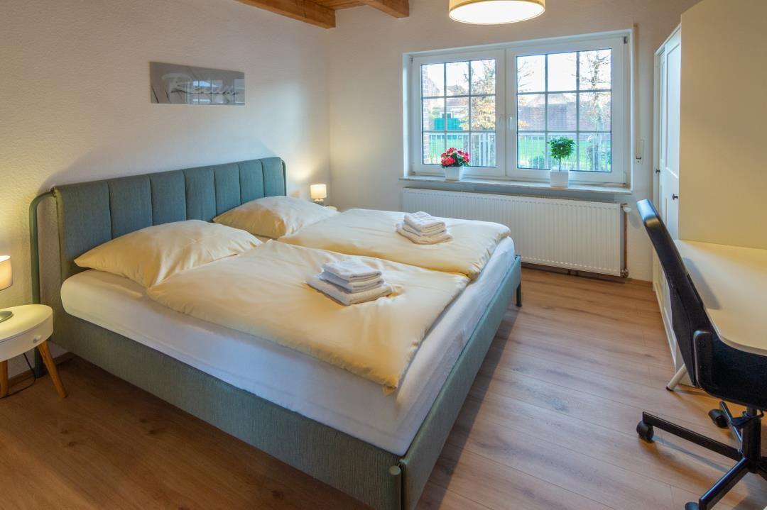 Bedroom with double bed, desk, and window overlooking garden.