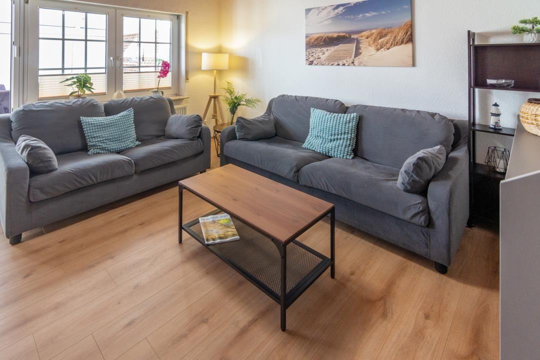 Living room with two gray sofas, wooden floor, and coffee table.