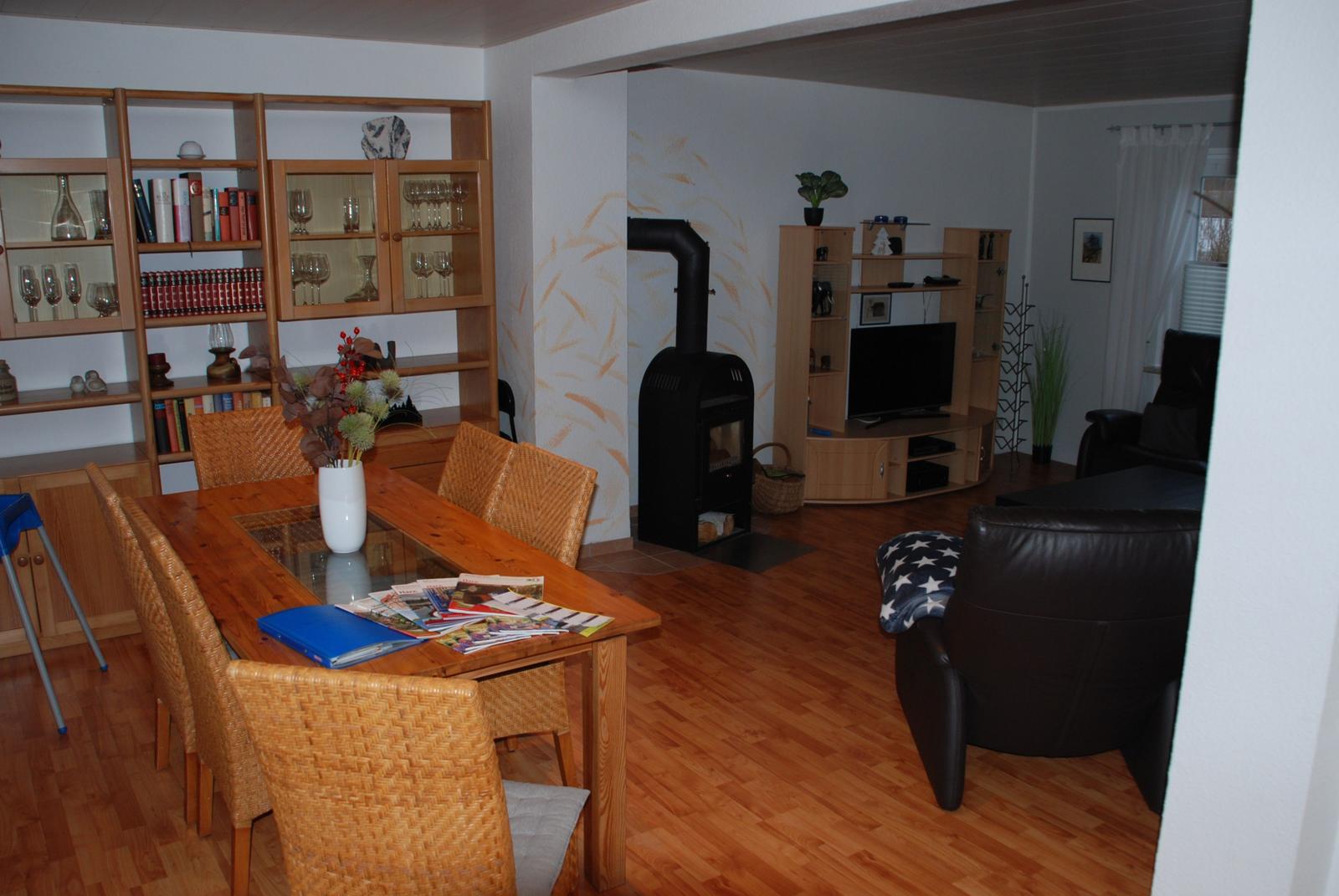 Esszimmer mit Tisch und Stühlen. Wohnbereich mit Sofa, Fernseher und Kamin.