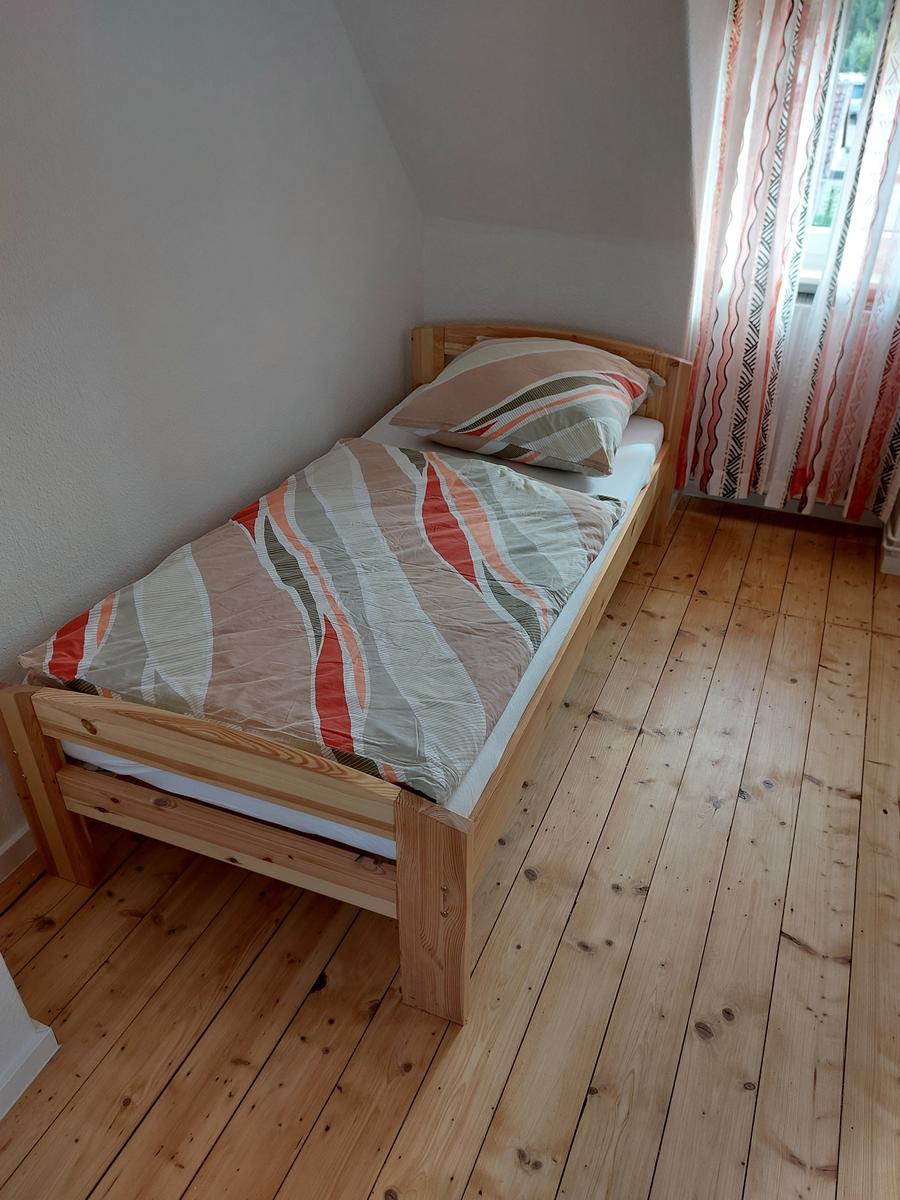 Ein Schlafzimmer mit einem Holzbett, einem Fenster mit Vorhängen und einem Holzboden.