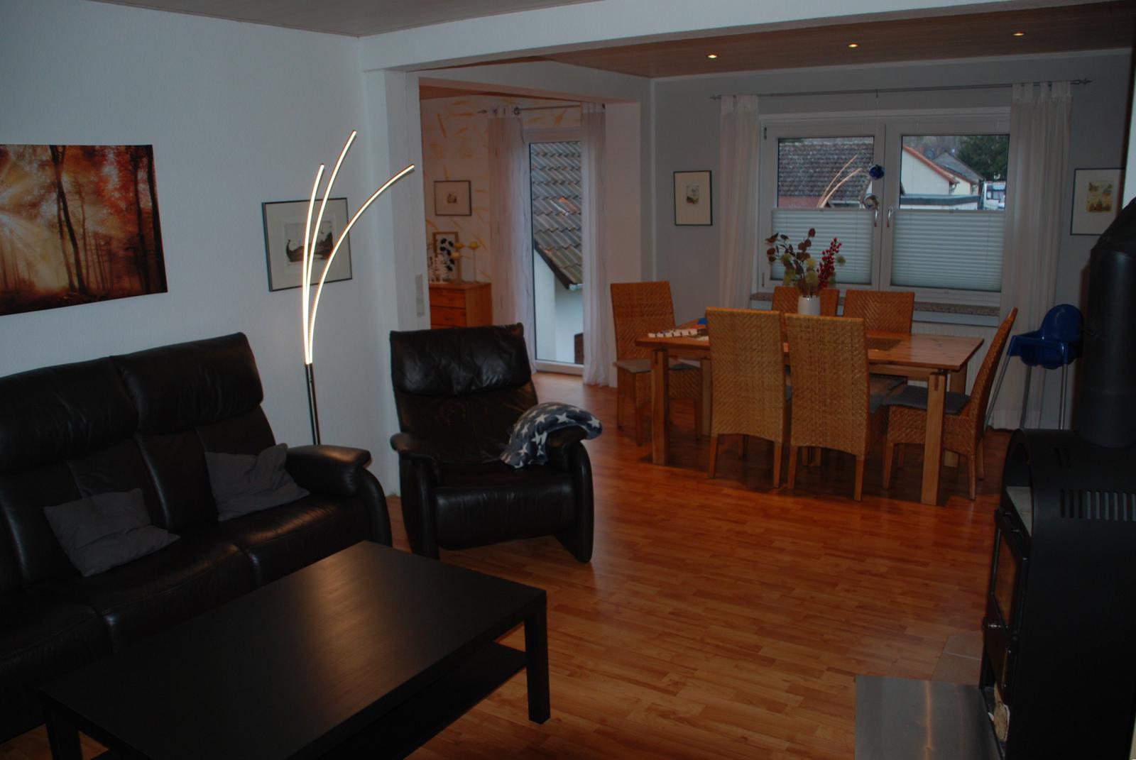 Wohn- und Essbereich mit Ledersofa, Esstisch und Holzboden.