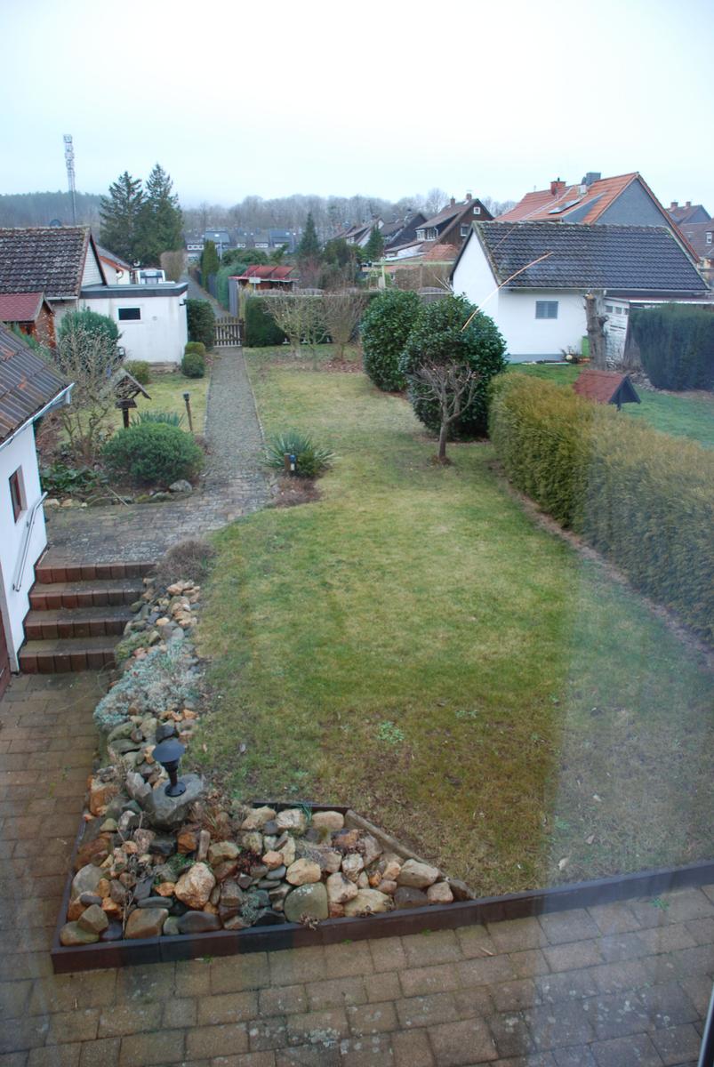 Garten mit Rasenfläche, Steingarten und Pfad zwischen Häusern.