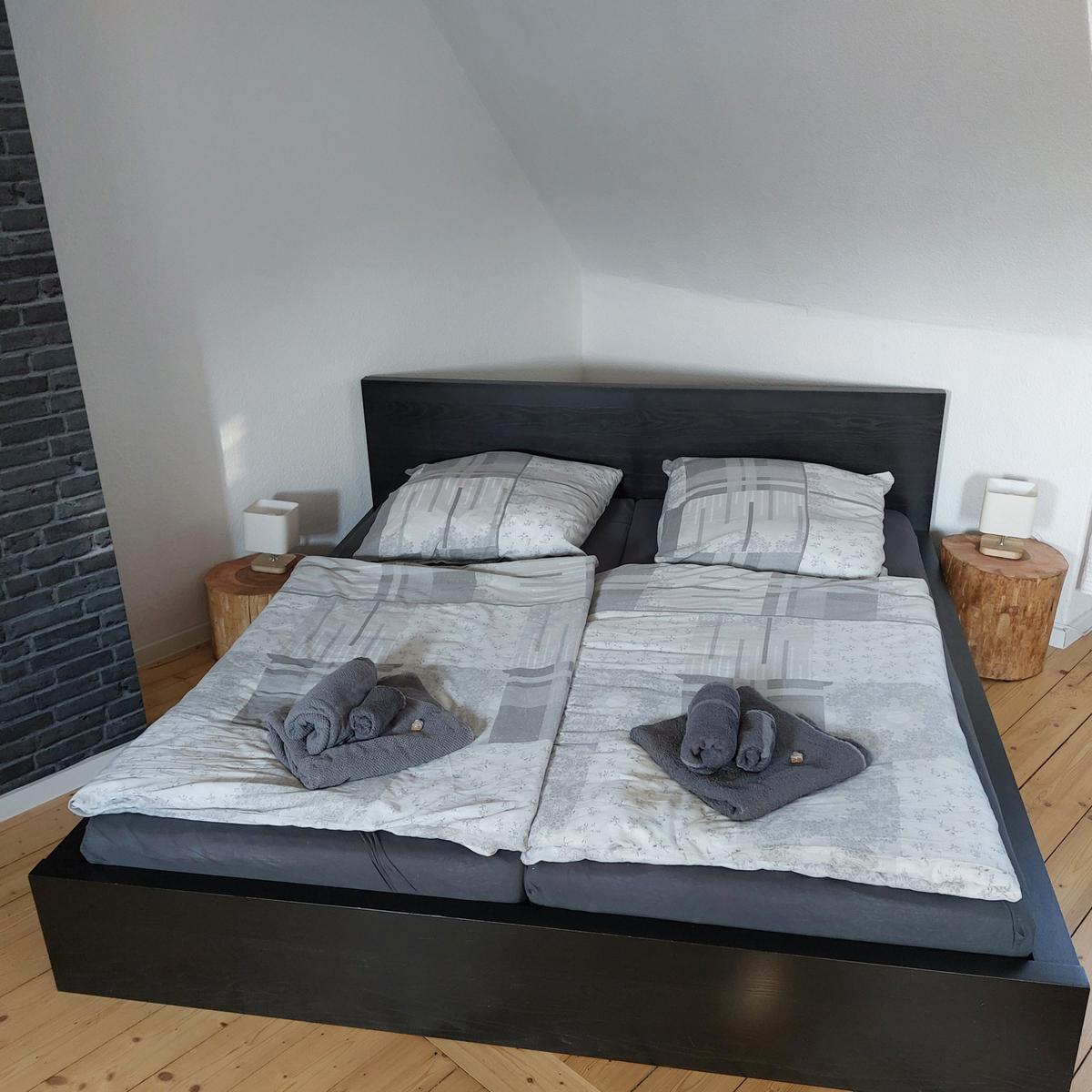 Schlafzimmer mit Doppelbett, zwei Nachttischen und Holzboden.